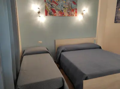 a small room with two beds and two lights at ROMECOMING Ostiense Guest House in Rome