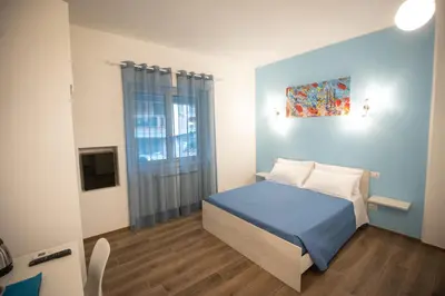 a bedroom with a blue bed and a window at ROMECOMING Ostiense Guest House in Rome