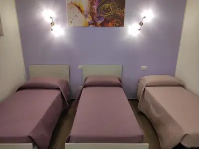 two beds in a room with purple walls at ROMECOMING Ostiense Guest House in Rome