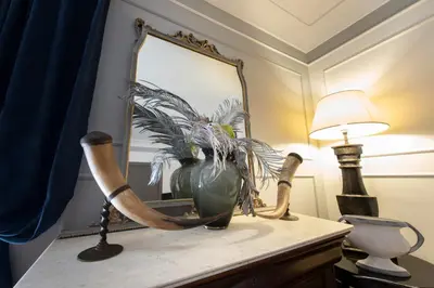 a table with a vase and a lamp and a mirror at Germanico Charming Maison in Rome