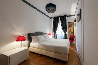 a bedroom with a white bed and a red chair at Germanico Charming Maison in Rome