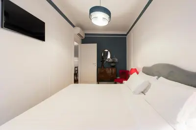 a bedroom with a large white bed and a blue wall at Germanico Charming Maison in Rome