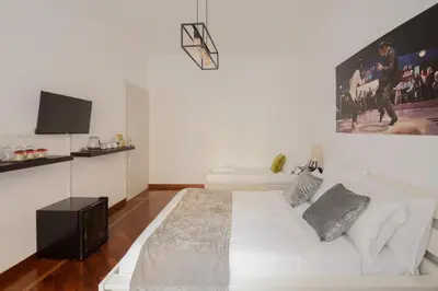 a bedroom with a white bed and a flat screen tv at Pop Corn Vatican Suites in Rome