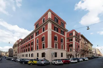 a red and white building with cars parked in a parking lot at Vatican Night Suites in Rome