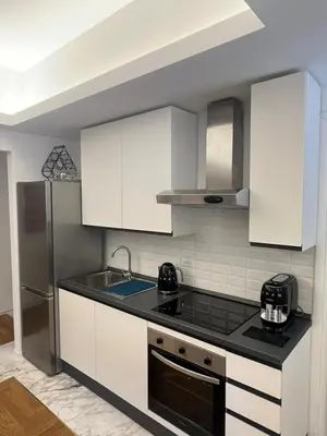 a kitchen with white cabinets and a black counter top at Savoia House, modern apartment near Villa Borghese in Rome
