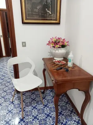 a table with a white chair and a vase on it at House Vaticano in Rome