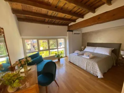 a bedroom with a bed and a couch and windows at Margutta Domitia Home in Rome