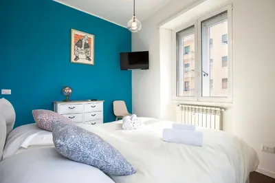 a bedroom with a large white bed with a blue wall at Piramide Family Apartment Rome in Rome