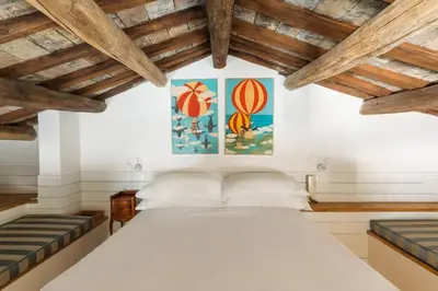 a bedroom with a large white bed and wooden ceilings at Casa Adriana, a Burghesius home in Rome