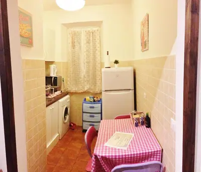 a small kitchen with a table and a refrigerator at Casa Tua sul Tetto di Roma in Rome