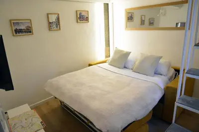a bedroom with a bed with white sheets and pillows at Petit loft de Rome Vatican Apartment in Rome