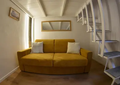 a yellow couch in a room with a shelf at Petit loft de Rome Vatican Apartment in Rome