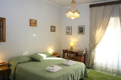 a bedroom with a green bed and a chandelier at B&B Rome Downtown Deluxe in Rome