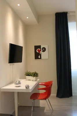 a white desk with a red chair and a television at Little Rose Lodge in Rome