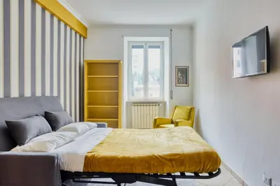 a bedroom with a bed and a couch and a tv at Yellow Stripes Apartment - San Giovanni by RHR in Rome