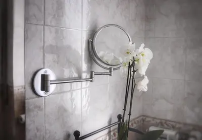 a bathroom with a mirror and a vase of flowers at ROMA BeMa Apartment - charme e relax a due passi dal Vaticano in Rome