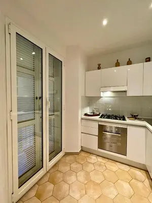 a kitchen with white cabinets and a large window at Professor's house in Porta Pia in Rome