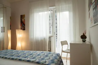 a bedroom with a bed and a chair and a window at Domus Antonia in Rome