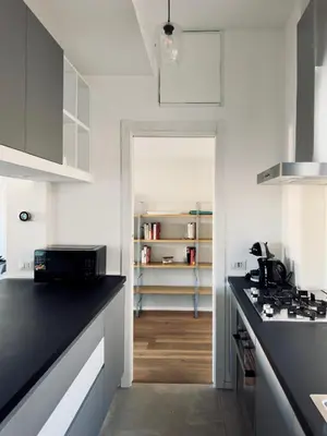 a kitchen with white cabinets and a black counter top at The Twenty - Villaggio Olimpico apartment in Rome