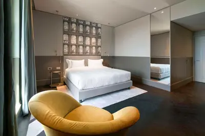 a bedroom with a bed and a chair and a bed at Radisson Collection Hotel, Roma Antica in Rome