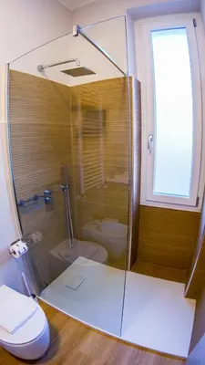 a bathroom with a glass shower with a toilet at Baronio Apartment in Rome