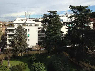 a white building with trees in front of it at Room In Roma Isole in Rome