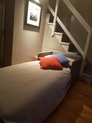 a bed with an orange pillow sitting next to a staircase at Assunta Domus in Rome