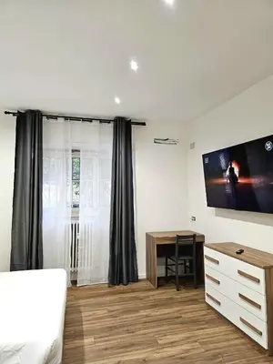 a bedroom with a desk and a tv on the wall at Ricettiva Cipro San Pietro e Musei Vaticani in Rome