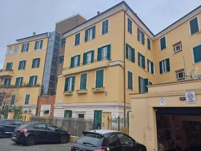 a large yellow building with cars parked in front of it at Gianicolo Sweet Home in Rome