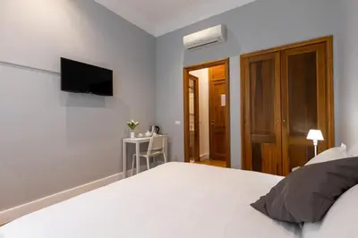 a white bedroom with a bed and a television at River61 - Guest House in Rome
