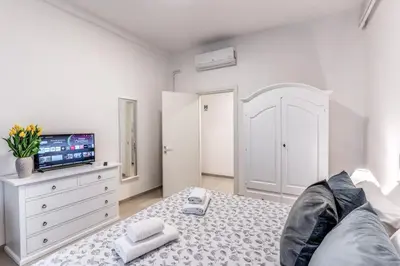a white bedroom with a bed and a tv at PMT Apt in Rome