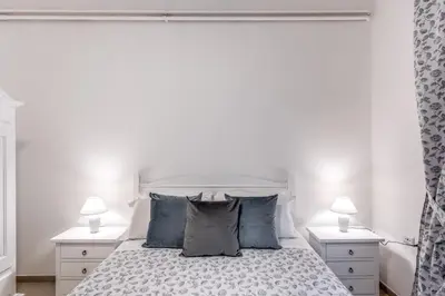 a white bedroom with a white bed with blue pillows at PMT Apt in Rome