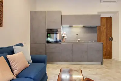 a living room with a blue couch and a kitchen at Luxury apartment in Rione Monti in Rome