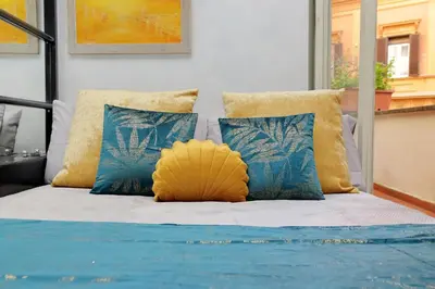 a bed with blue and yellow pillows on it at Charming loft with terrace at the Quirinale in Rome