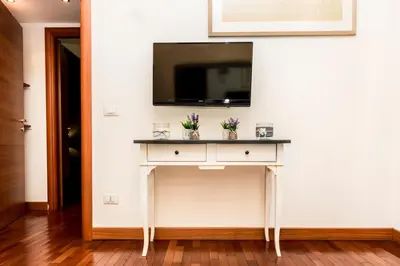 a white console table with a tv on a white wall at S. Peter 2 - Apartment with garden -50m from metro in Rome