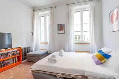 a bedroom with a bed and a tv and windows at Flaminio Historic Charm and Modern Flair in Rome
