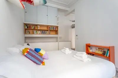 a bedroom with a white bed with a book shelf at Flaminio Historic Charm and Modern Flair in Rome