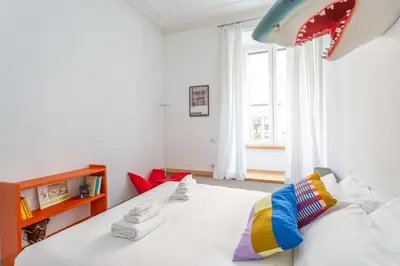 a bedroom with a bed with white sheets and a window at Flaminio Historic Charm and Modern Flair in Rome