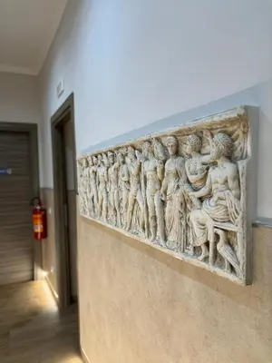 a stone relief of people on a wall in a hallway at Casa Mirabilia in Rome