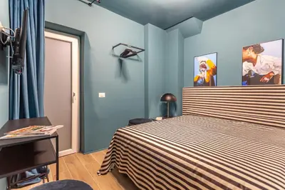 a bedroom with blue walls and a bed with a striped bedspread at Daplace - Elena Apartment in Rome