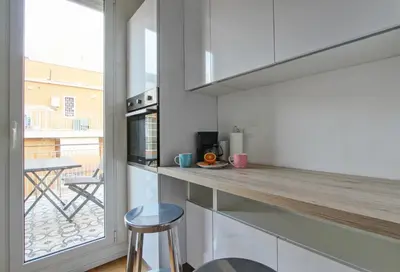 a kitchen with white cabinets and a counter with a table at Design Monteverde Flat in Rome