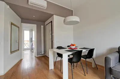 a dining room with a white table and black chairs at Design Monteverde Flat in Rome