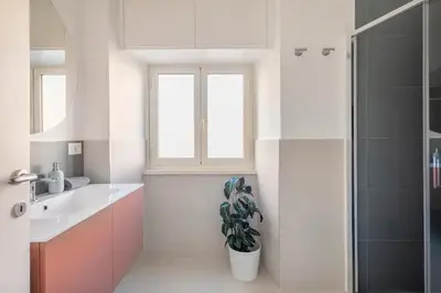 a bathroom with a sink and a shower and a potted plant at Appartamento “La Palma nel Cortile” in Rome