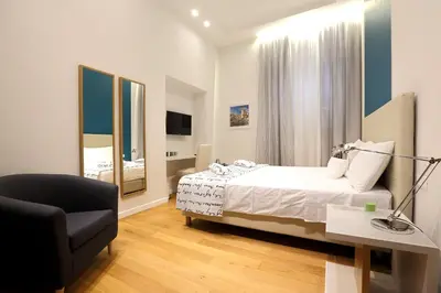 a bedroom with a bed and a chair and a desk at Sofia's Suites Guesthouse in Rome