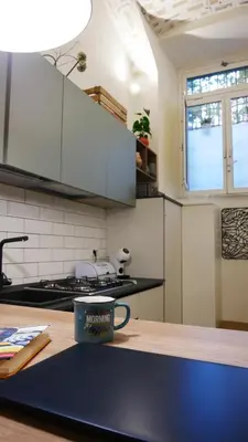 a kitchen with white cabinets and a coffee mug on a counter at Vera Roma Suite&Apartment - Charming 3 bedroom apt - 20min walk from Colosseum in Rome