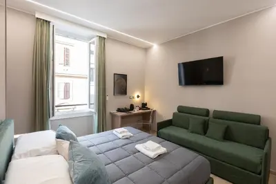 a living room with a bed and a couch and a television at IRON Luxury Rooms in Rome
