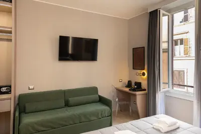 a living room with a green couch and a tv on the wall at IRON Luxury Rooms in Rome