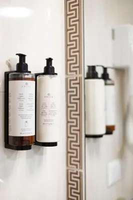 three bottles ofodorizers on a wall next to a mirror at Domus Vitra 23 in Rome