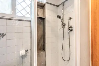 a shower in a bathroom with white tiles at Residenza Coppedè in Rome