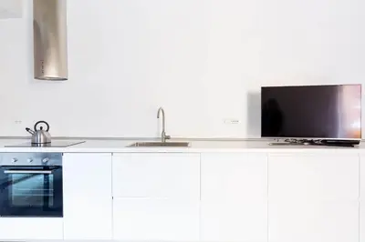a kitchen with white cabinets and a flat screen tv at Campo 13 Holiday Apartment in Rome
